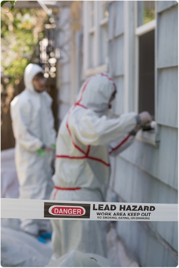 Two house painters in hazmat suits removing lead paint from an old house. Image  Copyright: Jamie Hooper / Shutterstock