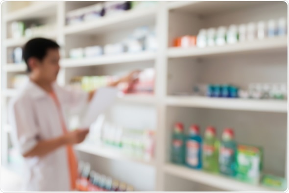 Blur image of pharmacist taking medicine from shelf in the pharmacy - Image Copyright: Kwangmoozaa / Shutterstock