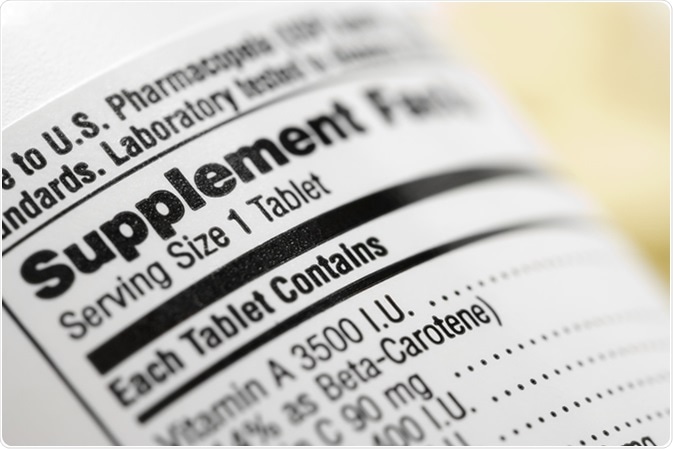 Close up de uma etiqueta do suplemento dietético que alista as vitaminas contidas dentro de cada tabuleta. Crédito de imagem: iofoto/Shutterstock