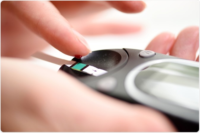 Diabetes patient measuring glucose level blood test use glucometer and small drop of blood from finger and test strips. Image Credit: Harisn / Shutterstock