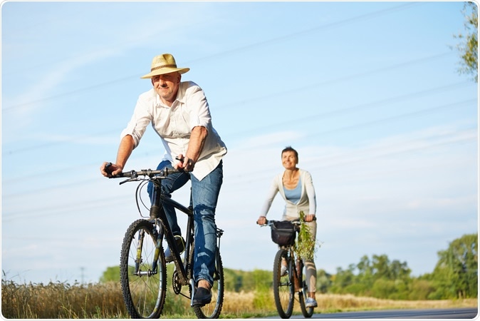 Senior couple cycling with bikes in nature in summer. Image Credit: Robert Kneschke / Shutterstock