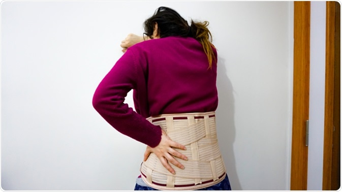 Woman with girdle for back pain. Image Credit: Akin Ozcan / Shutterstock