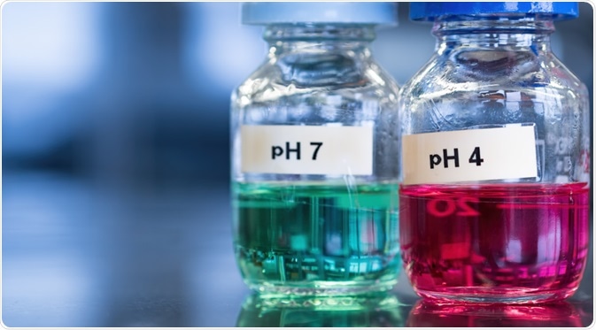 Two glass bottles in laboratory, one containing an acidic solution of pH 4 and the other containing a basic solution of pH 7.