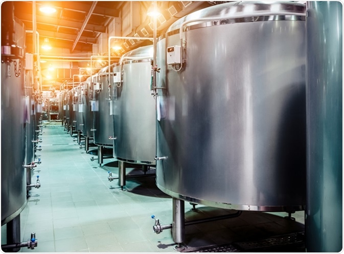 Modern Beer Factory. Rows of steel tanks for beer fermentation and maturation. Image Credit: Nordroden / Shutterstock