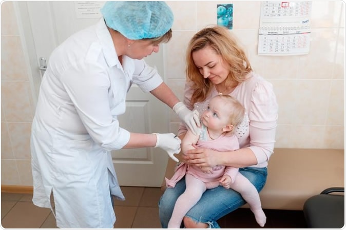 15 mesi, tenuti tramite sua madre, essendo amministrando la sua prima dose del vaccino di parotite epidemica, di morbillo e di rosolia (MMR). Credito di Imaeg: UNICEF/UN0201055/Krepkih
