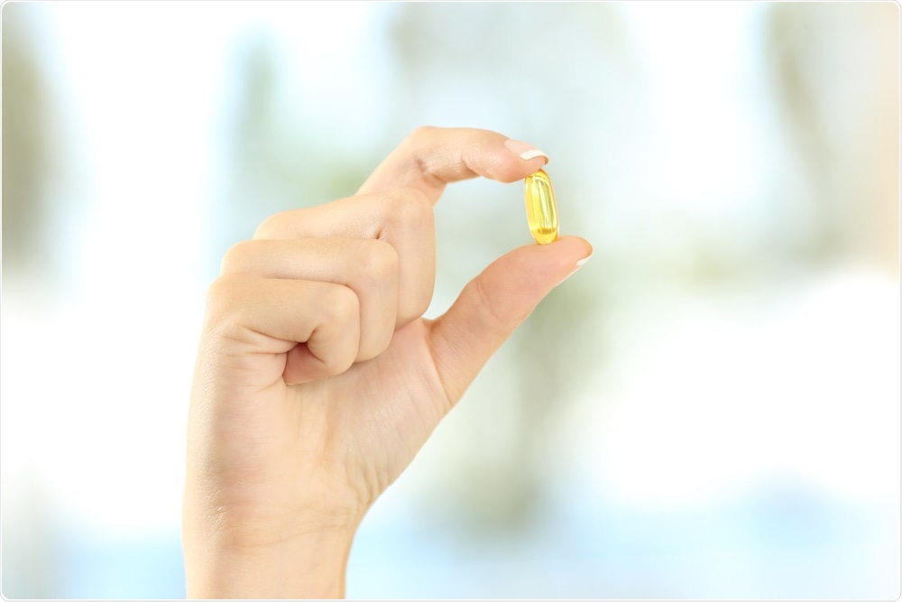 Woman holding a vitamin D supplement.