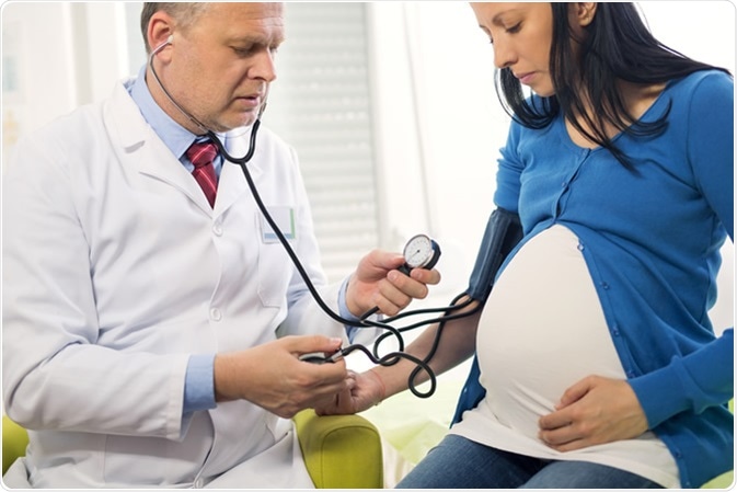 Medico che misura la pressione sanguigna di una donna incinta. Credito di immagine: adriaticfoto/Shutterstock