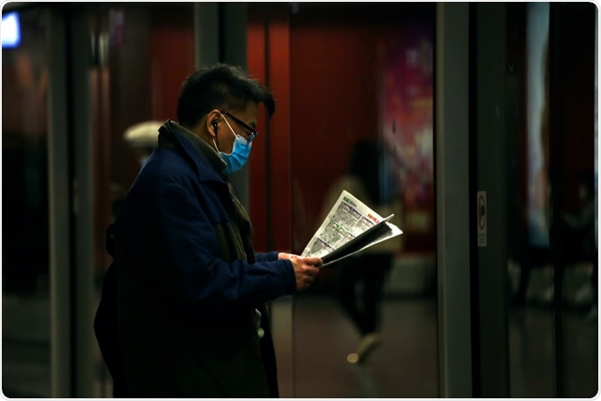Hong Kong - January 29, 2020: A man wearing a surgical face masks reads the newspaper while waiting for the MTR. A rise in face masks followed reports of the Wuhan Coronavirus in Hong Kong. Image Credit: Katherinekycheng / Shutterstock