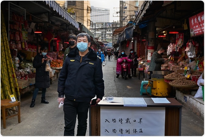 Chengdu/China-Feb.2020: A security guard with face mask outside a local wetmarket. Image Credit: Amar Shrestha / Shutterstock
