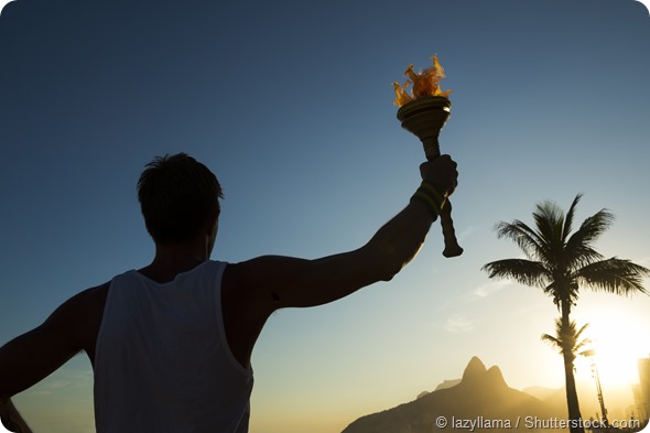 Silhouette of athlete standing with sport torch at the Rio de Janeiro Brazil sunset skyline at Ipanema Beach