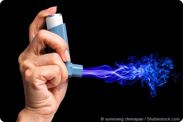 hand holding asthma inhaler with smoke on black background