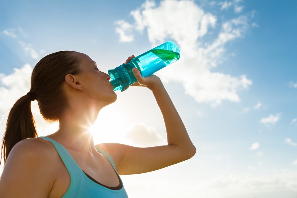 Young female drinking a bottle of water. Image Credit: KieferPix/Shutterstock.com
