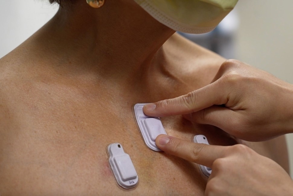 A health care worker places the wearable devices across a patient